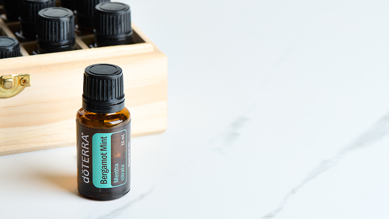 A bottle of dōTERRA Bergamot Mint in front of a box of essential oils.