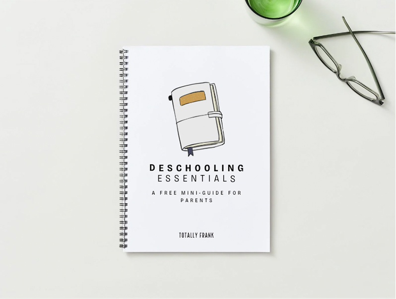 A spiral-bound notebook titled “Deschooling Essentials: A Free Mini-Guide for Parents” lies on a white surface beside a pair of glasses and a green cup. The minimalist cover features an illustration of a closed journal. The image promotes a practical homeschooling resource for parents transitioning into deschooling.