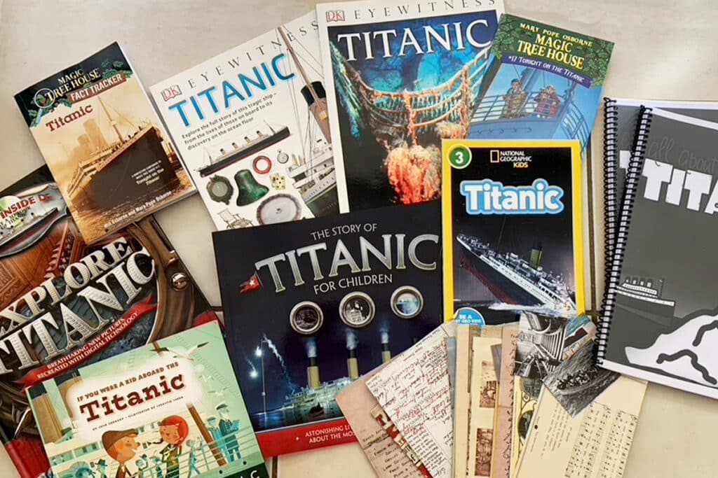 Collection of Titanic themed children’s books, activity guides, and printed materials spread across a table alongside a notebook. The variety of resources reflects what do I need to homeschool my child, showing that while it can seem like a lot, meaningful learning can start with just a few simple materials.